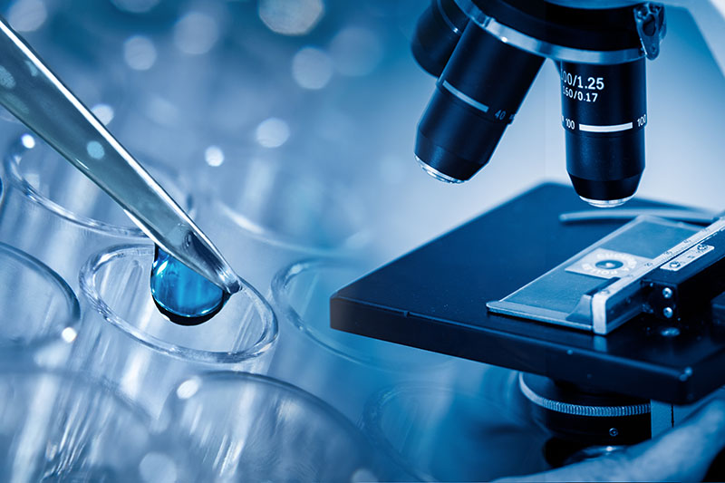 Microbiologist examining slide with help of compound microscope. blue toned images.